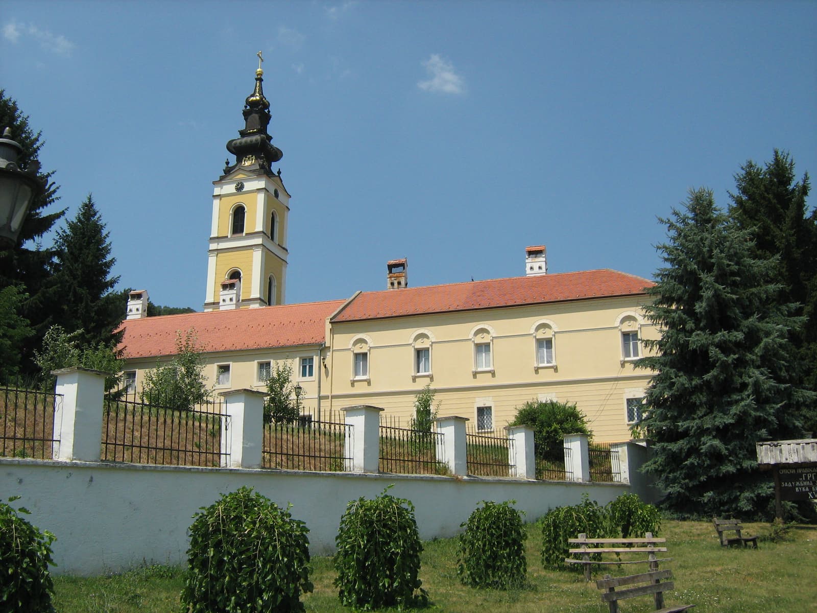 Grgeteg Monastery with its baroque bell tower behind a white fence