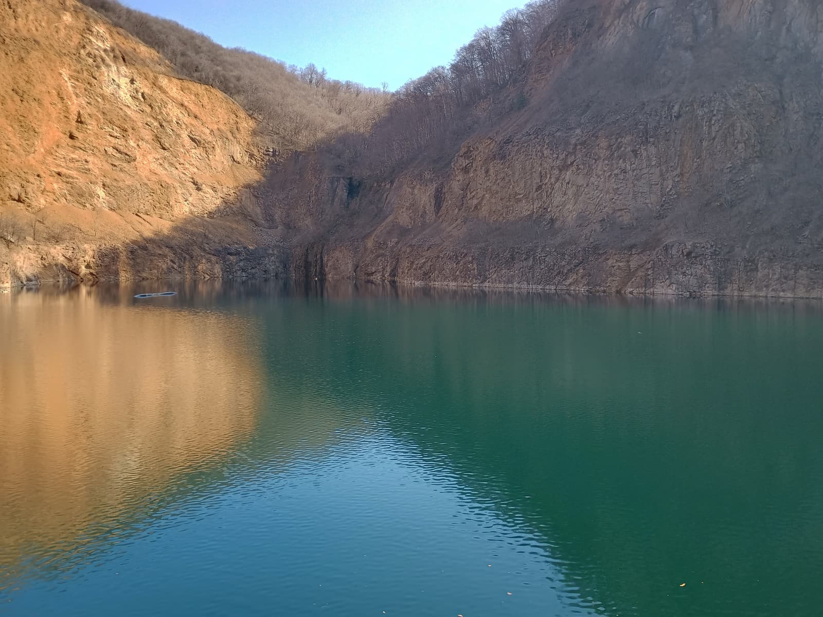 The green-blue water of Ledinci Lake below the rock walls of the old quarry